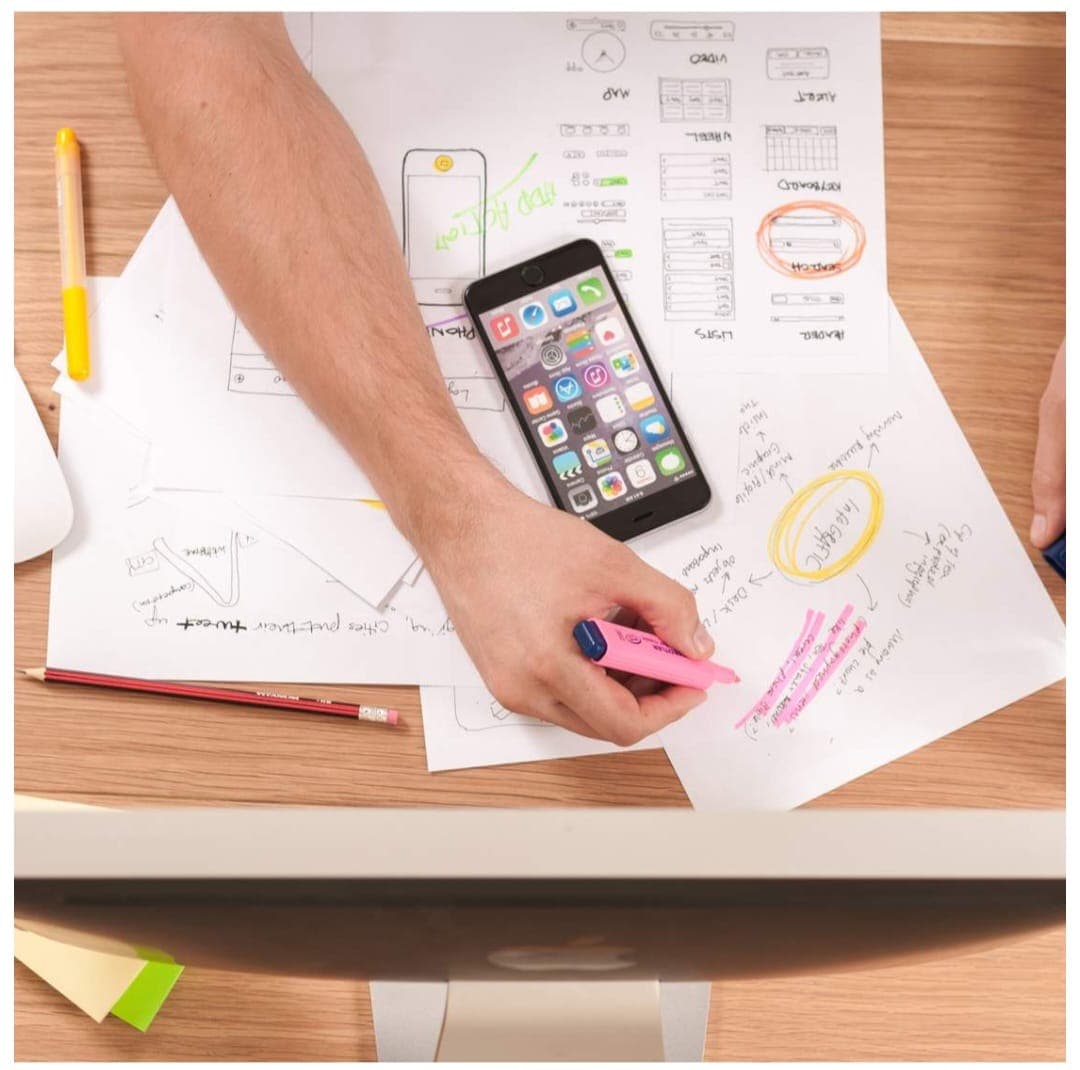 Hand sketching app wireframes and notes on a desk with a smartphone